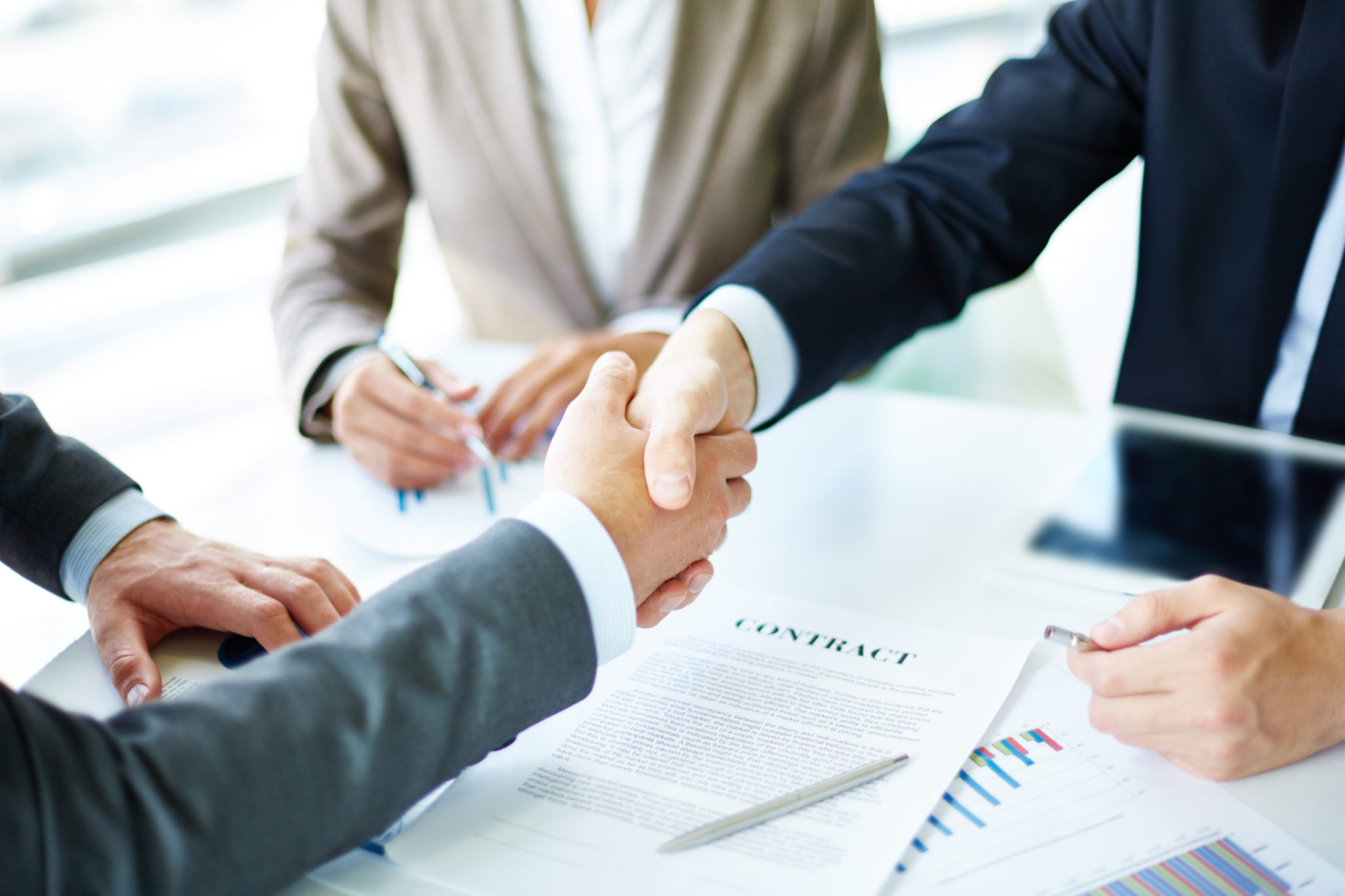Making agreement Image of business partners handshaking over business objects on workplace